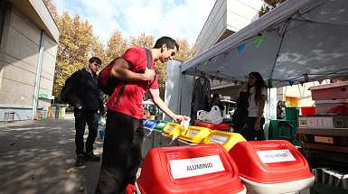 Personas botando residuos en contenedores para reciclar.