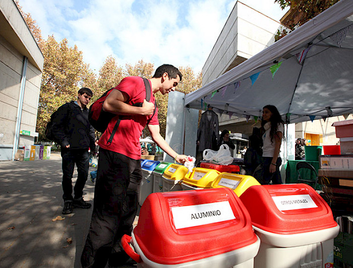 Personas botando residuos en contenedores para reciclar.