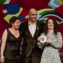Foto tres personas, dos mujeres y un hombre, en una ceremonia de premiación en España.