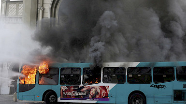 Bus azul con blanco siendo quemado.