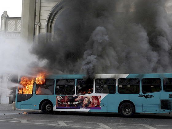 Bus azul con blanco siendo quemado.