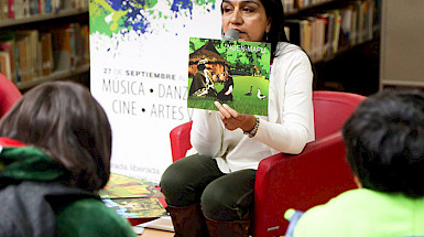 Maria Lara reading a book to children in a library