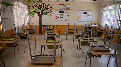 Sala de clases vacía con las sillas sobre las mesas