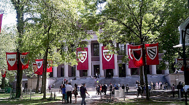 a group of people standing in front of a building with red and white flags