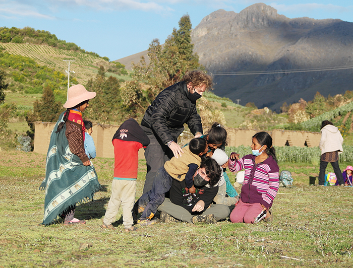 Two volunteers are playing in the grass with a group of six kids in Peru.