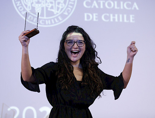 Macarena Tejos feliz y sonriente, levantando el galvano de ganadora.