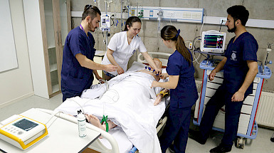 Four nurses (two women and two men) are practicing with a patient simulator.