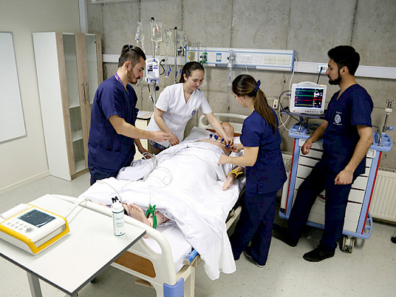 Four nurses (two women and two men) are practicing with a patient simulator.