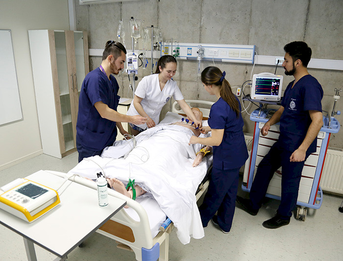 Four nurses (two women and two men) are practicing with a patient simulator.