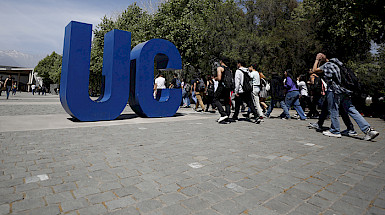 personas caminando al lado de dos letras grandes: U y C