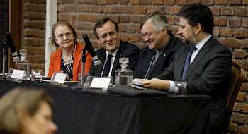 Tres hombres y una mujer sentados a la mesa.