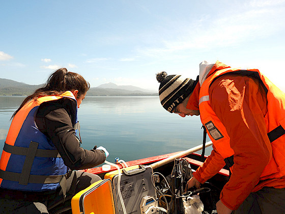 A woman and a man are investigating in a boat in the Aysén Region.