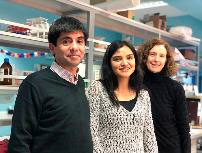 Three people are smiling in front of a lab. From left to right: Jorge Campusano, Francisca Roja and María Paz Marzolo.