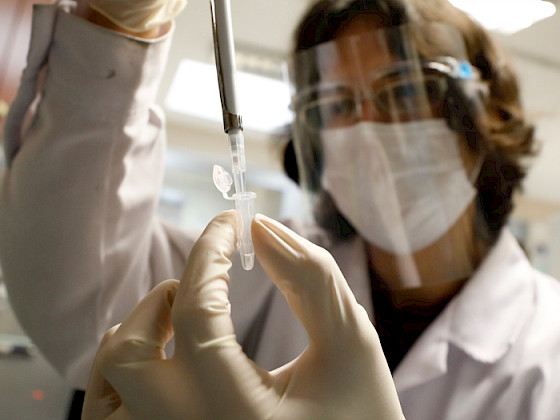 Scientist with mask handling a pipette.