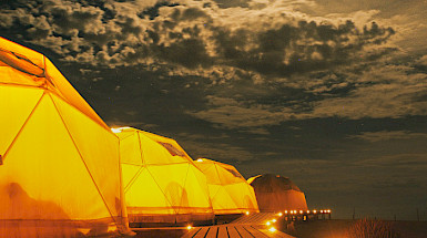 a row of yellow tents on a wooden walkway at night