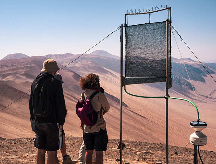 A group of four people is checking the network of fog-measuring device in the Atacama Desert.
