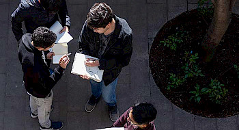 hombres jóvenes leyendo de pie en un patio