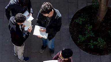 hombres jóvenes leyendo de pie en un patio