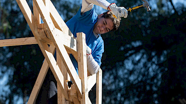 Student hammering on the roof of a chapel under construction