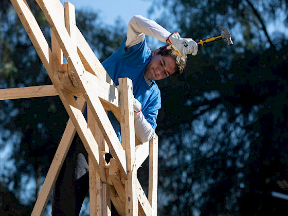 Student hammering on the roof of a chapel under construction