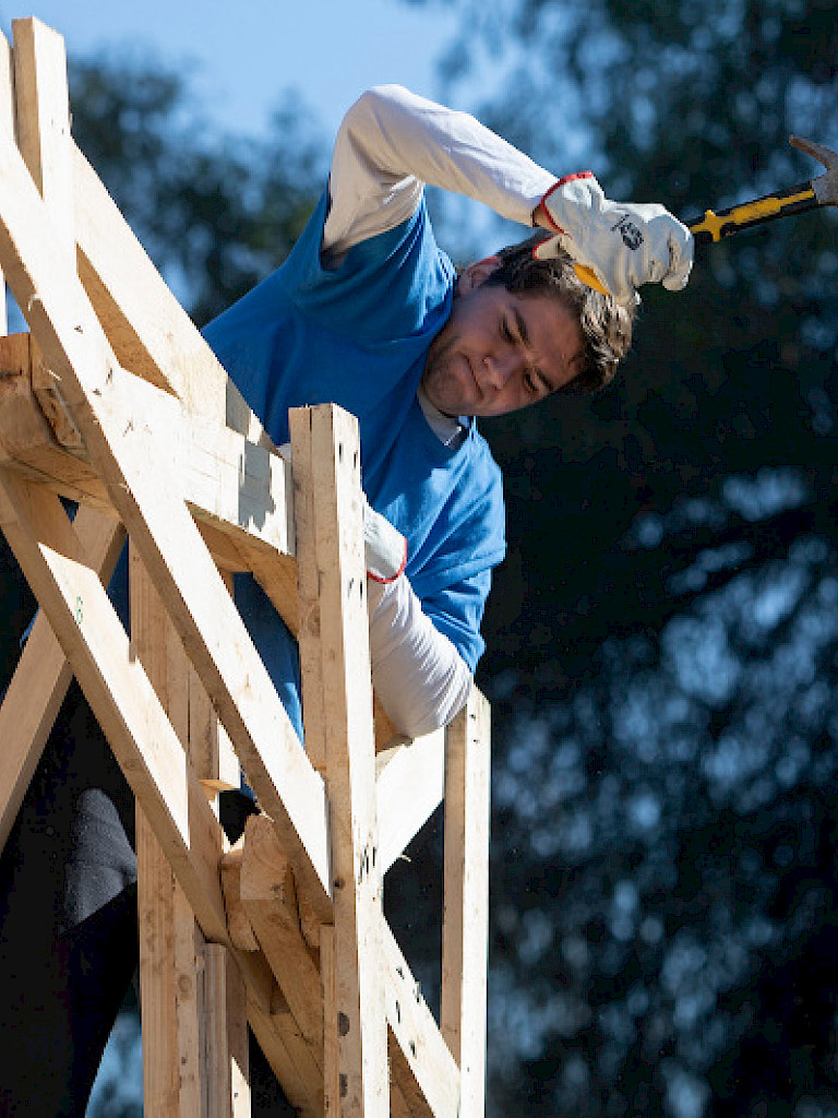 Student hammering on the roof of a chapel under construction