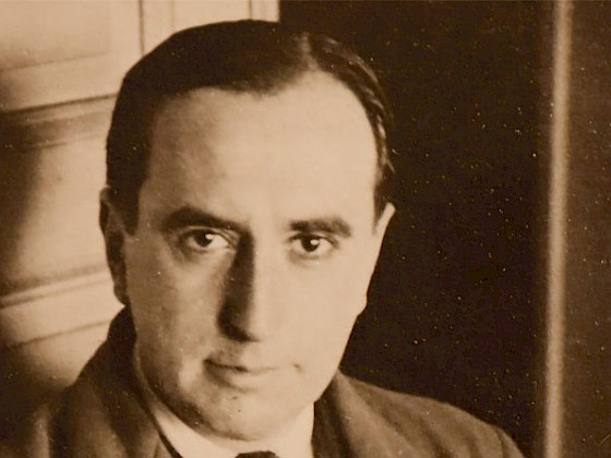 The Chilean writer and poet Vicente Huidobro is posing with a serious face. The photography is sepia.