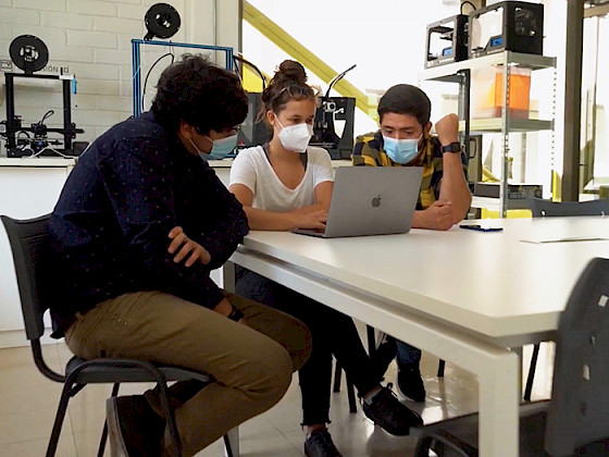 Two young men and one woman are discussing during a manufacturing workshop.
