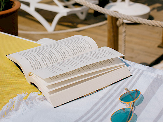 Un libro sobre una mesa en verano junto a unos lentes de sol
