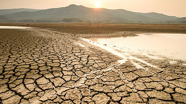 Tierra agrietada y un lago con agua escasa.