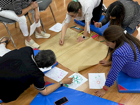 mujeres sentadas en el sueloescribiendo en papeles