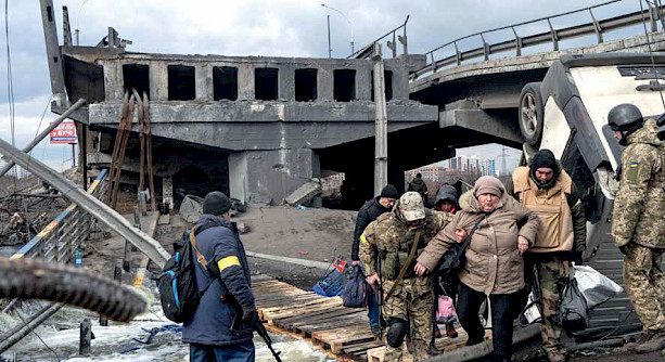 Members of the Ukrainian Army assist residents crossing a destroyed bridge.