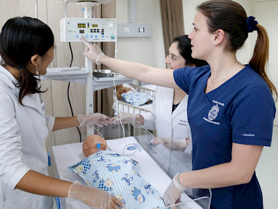 nursing teacher demonstrating how to watch a monitor to two female students