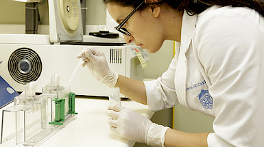 Científica manipulando una pipeta en un laboratorio.
