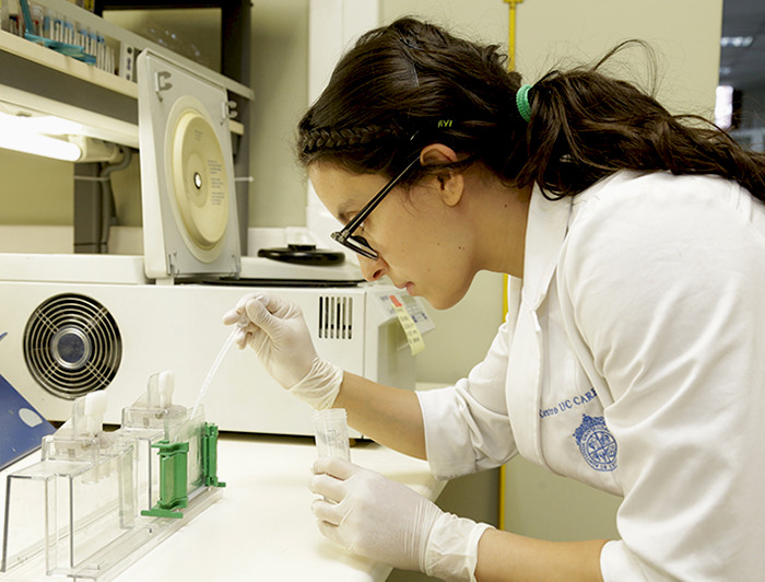Científica manipulando una pipeta en un laboratorio.