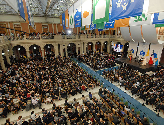 Un salón lleno de gente escuchando al Papa Francisco.