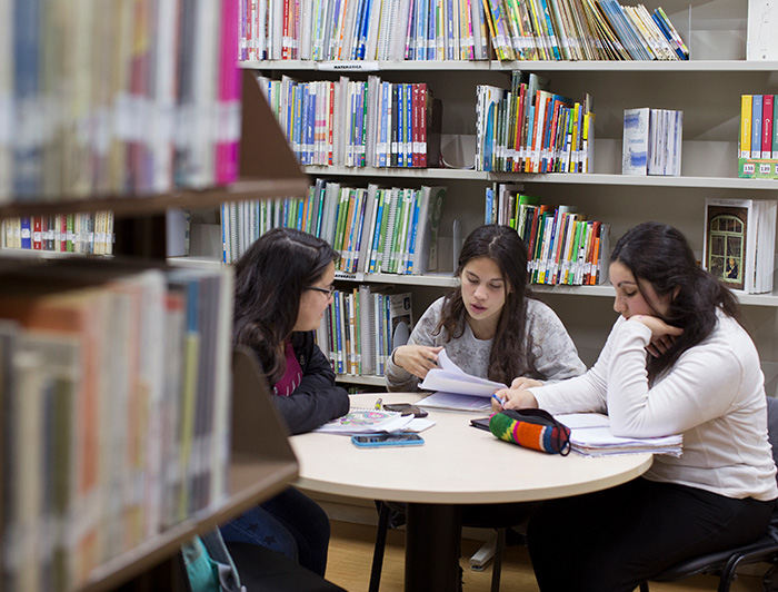 Alumnas estudian en una biblioteca sentadas en una mesa