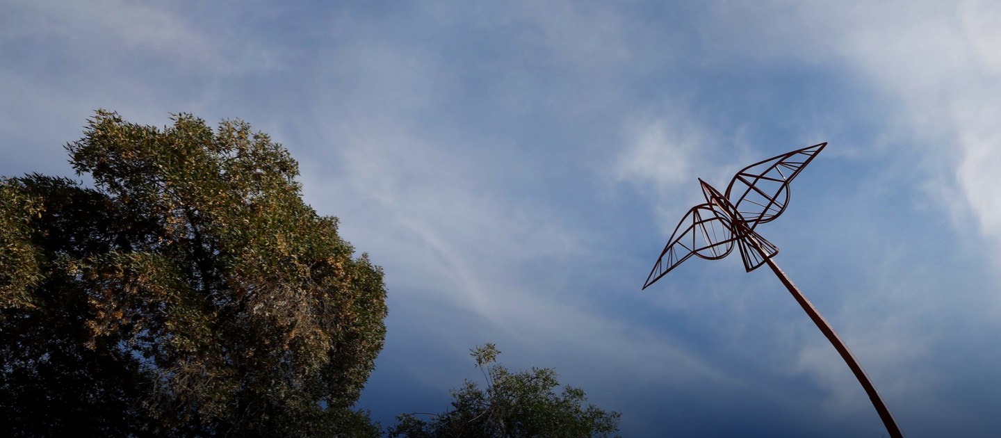 Escultura de paloma metálica contra el cielo.