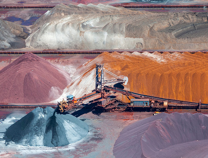 Faena minera que muestra una maquinaria y relaves de distintos colores