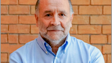 Portrait of Luis Cifuentes. In the background is a brick wall.