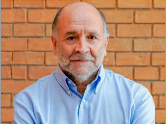Portrait of Luis Cifuentes. In the background is a brick wall.