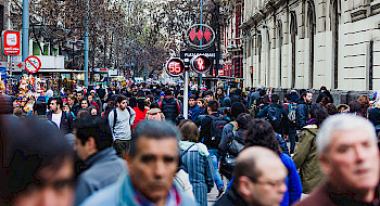 Gente caminando por la calle en el centro De Santiago con el símbolo del metro al fondo