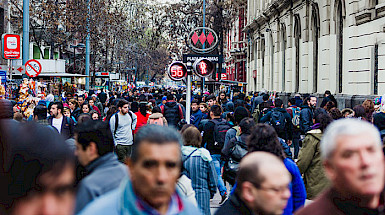 Gente caminando por la calle en el centro De Santiago con el símbolo del metro al fondo