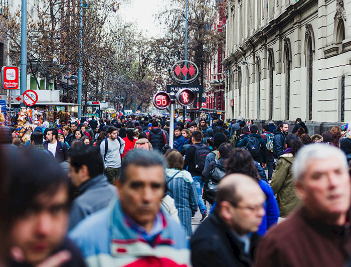 Gente caminando por la calle en el centro De Santiago con el símbolo del metro al fondo