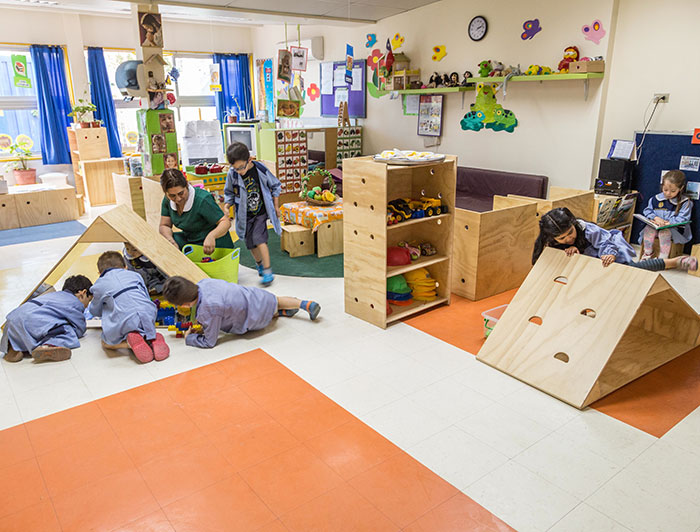 Niños juegan en una sala con muebles de madera del proyecto MAFA