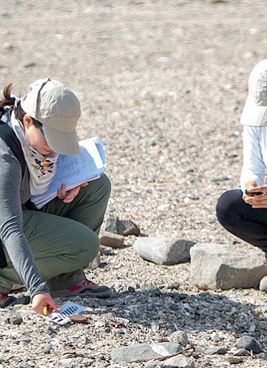 Two students measure an archaeological piece in the desert