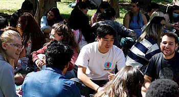 Estudiantes internacionales conversan sentados en el patio del Campus San Joaquín UC.