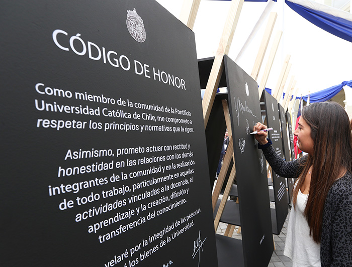 Joven firmando el Código de Honor en unas pizarras negras.