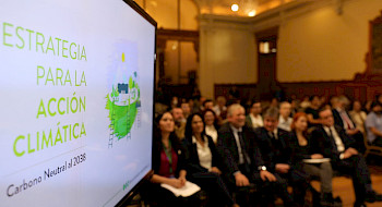 Ceremonia de lanzamiento de la Estrategia para la Acción Climática en que se ve el público y una pantalla con la portada del documento.