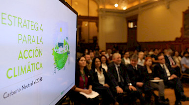 Ceremonia de lanzamiento de la Estrategia para la Acción Climática en que se ve el público y una pantalla con la portada del documento.