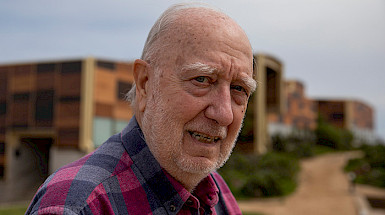 Fotografía de retrato de Juan Carlos Castilla con la Estación Costera de Investigaciones Marinas de fondo.